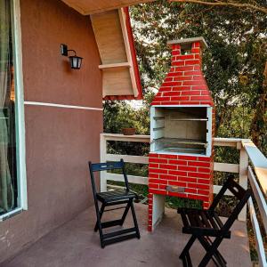 un forno in mattoni rossi su un portico con due sedie di Chale da Montanha Capivari a Campina Grande do Sul Altre 70 foto