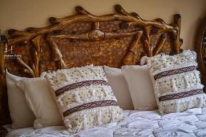 a bed with white pillows and a wooden headboard at Tynass Ferme - Atlas Room Fes in Douar er Rouazi