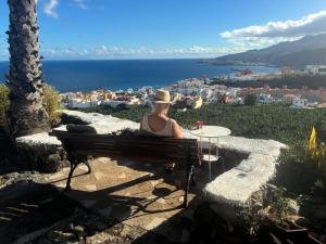 a woman sitting on a bench looking at the ocean at El Sueño Del Angel in Santa Cruz de la Palma