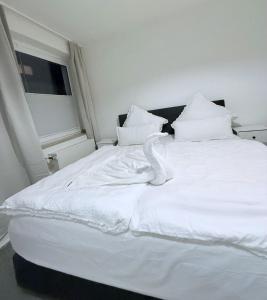 Seibel's SUITES - Exclusive Flat Krefeld City - GA - ROOFTOP في كريفيلد: سرير ابيض عليه بجعة بيضاء
