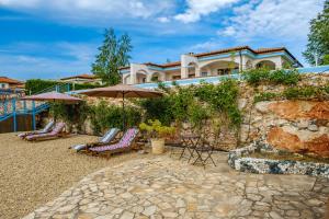 una casa con una pared de piedra, sillas y sombrillas en Villa Parnas at Lighthouse Golf by Parnas Estate, en Balchik
