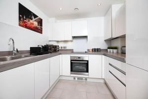 a white kitchen with a sink and a stove at Stunning 2BR flat with balcony in Maidenhead