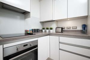 a kitchen with white cabinets and stainless steel appliances at Stunning 2BR flat with balcony in Maidenhead