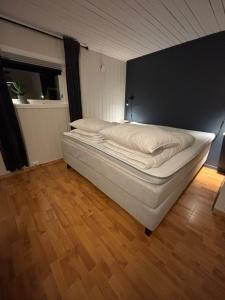 a white bed in a room with a wooden floor at Strandveien apartment in Narvik
