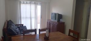 Una sala de estar con una mesa y un televisor. en Brisas, en Santa Teresita