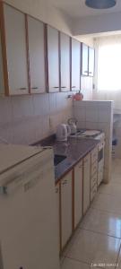 Una cocina con gabinetes blancos y encimeras negras. en Brisas, en Santa Teresita