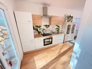 a kitchen with white cabinets and wooden floors at Chalet im Wald mit Sauna in Schönwalde