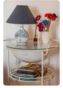a lamp on a glass table with books and flowers at Casa na Floresta in Figueira da Foz