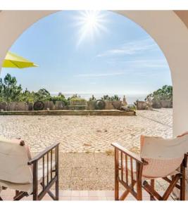 a couple of chairs and an umbrella on a beach at Casa na Floresta in Figueira da Foz