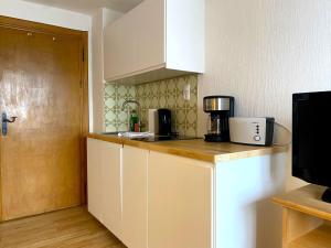 Eine Küche mit weißen Schränken und einer Kaffeemaschine auf der Arbeitsplatte. in der Unterkunft Apartmenthaus am Tegernsee - Studios mit Küchenzeile und mit Bus erreichbar in Bad Wiessee