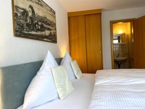 ein Schlafzimmer mit einem Bett mit weißen Laken und Kissen in der Unterkunft Apartmenthaus am Tegernsee - Studios mit Küchenzeile und mit Bus erreichbar in Bad Wiessee