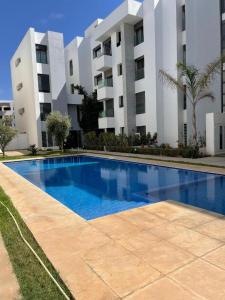 Grand Appart 3 chambres à 300 m de la Plage avec piscine et garage في تمارة: حمام سباحة أمام مبنى كبير