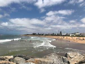 Grand Appart 3 chambres à 300 m de la Plage avec piscine et garage في تمارة: مجموعة من الناس في الماء على الشاطئ