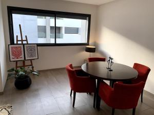 Grand Appart 3 chambres à 300 m de la Plage avec piscine et garage في تمارة: غرفة طعام بها طاولة وكراسي ونافذة