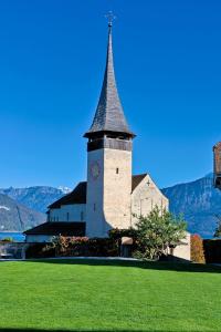 eine Kirche mit einem Kirchturm auf einer grünen Wiese in der Unterkunft Apartment Stockhorn in See- und Bergnähe, modern, mit Balkon, 4 Gäste in Einigen