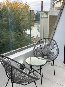 2 stoelen en een tafel op een balkon met een raam bij Contemporary 3-Bed Penthouse with River Views in Londen