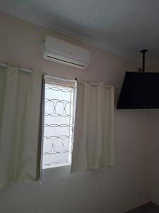 a room with a window with curtains and a fan at Hosting Altos da cidade perto de tudo in Bauru