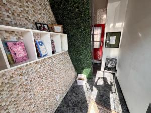 a hallway with a brick wall with a book shelf at Hosting Altos da cidade perto de tudo in Bauru