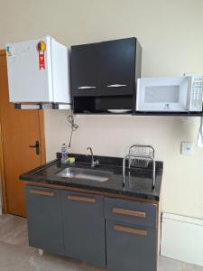 a kitchen with a sink and a microwave at Hosting Altos da cidade perto de tudo in Bauru +6 photos
