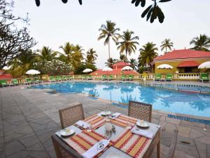 einen Tisch und Stühle vor einem Pool in der Unterkunft Mercure Goa Devaaya Resort in Velha Goa