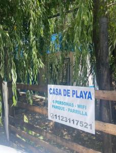 a sign on a wooden fence with a tree at Casa de Playa Mar de Ajo Castelli 1257 Beach House in Mar de Ajó