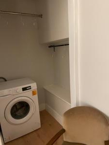 a laundry room with a washing machine and a chair at Cosy Coastal getaway 2 bed flat in Largs in Largs