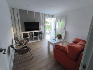 a living room with a red couch and a tv at Los Cala-Vivienda tranquila en casa unifamiliar in Vigo