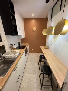 cocina con fregadero y encimera con taburetes en Le Cosy Grange Blanche - 2 chambres, en Lyon