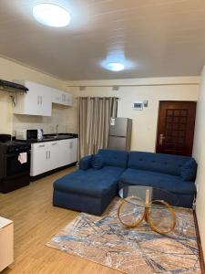 a living room with a blue couch and a kitchen at Budget apartments near American embassy in Lusaka