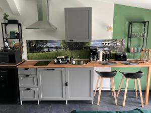 a kitchen with white cabinets and a counter with two stools at Ferienwohnungen Zur Biberburg in Friedrichswalde