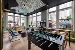 オークランドにあるJO&JOE Aucklandのフーズボールテーブルと椅子と窓のある部屋