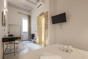 a bedroom with a bed and a desk and a television at Dione Ortigia in Siracusa