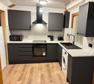 a kitchen with black cabinets and a washer and dryer at Fort William - Highland holiday home in Fort William +4 photos