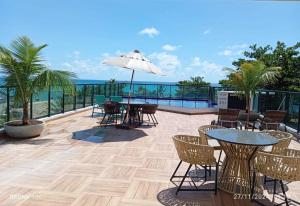 a patio with tables and chairs and the ocean at Flat Macaraípe - Maraca Beach I in Porto De Galinhas
