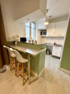 une cuisine avec un comptoir vert et des placards blancs dans l'établissement Le Cosy de Medipole, à Villeurbanne