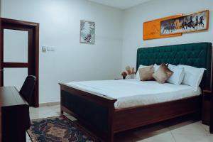 a bedroom with a large bed with a green headboard at Sasselo Hotel in Accra