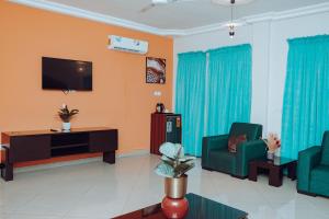 a living room with two green chairs and a tv at Sasselo Hotel in Accra +10 photos