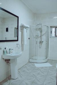 a white bathroom with a shower and a sink at Sasselo Hotel in Accra