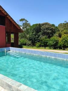 einem Pool mit blauem Wasser vor einem Gebäude in der Unterkunft POUSADA BELA HELENA in Visconde De Maua