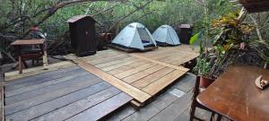 Commodity Camping Corazon Mazunte - Sol في مازونتي: ثلاث خيام على سطح خشبي مع طاولة