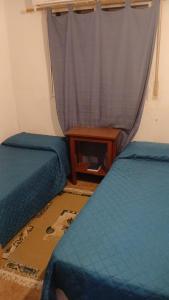 2 camas en una habitación con cortina y mesa en Hospedaje La Tuna, en Rocha