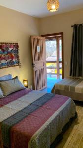 a bedroom with two beds and a sliding glass door at Casa Varanda do Toá Lapinha da Serra in Santana do Riacho +15 photos