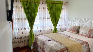 a bedroom with a bed with green drapes at Villa Santa Ines in Bogotá