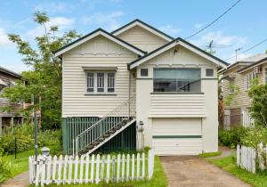 Comfortable 2 bedroom cottage في بريزبين: منزل أبيض مع سياج خشبي أبيض