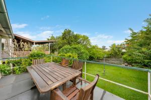 Comfortable 2 bedroom cottage في بريزبين: طاولة وكراسي خشبية على شرفة