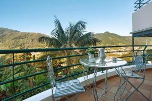 einen Tisch und zwei Stühle auf einem Balkon mit Bergblick in der Unterkunft traveller's house in Machico