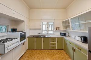 Comfortable 2 bedroom cottage في بريزبين: مطبخ مع دواليب خضراء وموقد الفرن العلوي