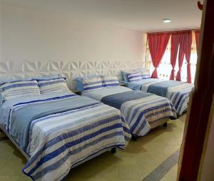 three beds in a room with blue and white sheets at Villa Santa Ines in Bogotá