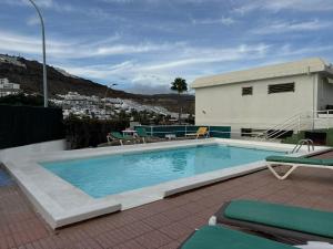 een zwembad met ligstoelen en een gebouw bij Puerto Rico Sea & Sun in Puerto Rico de Gran Canaria
