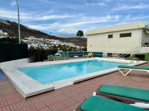 een zwembad met ligstoelen en stoelen naast een huis bij Puerto Rico Sea & Sun in Puerto Rico de Gran Canaria